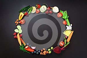 Healthy food background. Circle of organic vegetables, fruits, nuts, berries with copy space on black chalkboard. Top