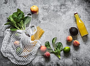 Healthy food background. Eco textiles bag, fruits, vegetables, herbs and empty notebook on a gray background, top view with copy