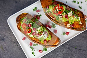 Healthy food - Baked sweet potatoes served with guacamole, feta cheese and pomegranate photo