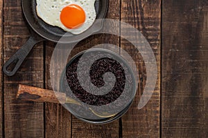 Healthy food black rice in bowl have fried egg in pan.