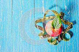 Healthy food concept. Apple and tape measure on wooden background