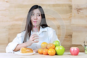 Healthy food concept. woman having breakfast with milk, fruit and bread at home. Smiling girl drinking fresh milk