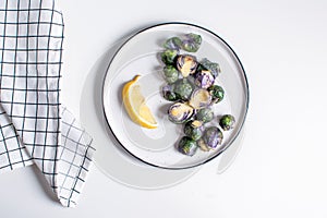 Healthy food concept, dieting, vegetarian, vegan - organic purple brussel sprouts fried on plate with lemon, top view