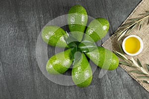 Healthy food concept. Fresh organic avocado, virgin olive oil and olive branches. Avocado with leafs on wooden table, top view, co