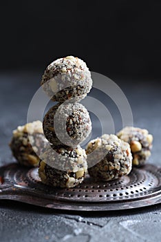 Healthy food concept. Homemade coconut energy balls on old metal tray on black background angle view