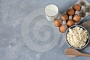 Healthy food concept, homemade cottage cheese, a glass of milk, yogurt and chicken eggs on a stone background, dairy products on d