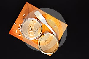 Healthy food concept homemake sunflower butter in glass jar by organic sunflower seeds on black background photo