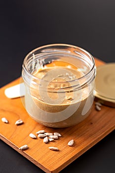 Healthy food concept homemake sunflower butter in glass jar by organic sunflower seeds on black background photo