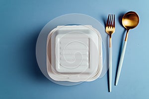 Healthy food concept: white burguer packaging closed with golden fork and spoon