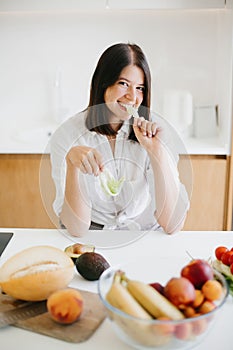 Healthy food concept. Young happy woman eating green lettuce leaf  and smiling on background of fresh fruits and vegetables in