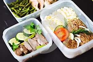 The healthy food in the containers on black background: snack, dinner, lunch. Baked fish, beans, beef cutlets, mashed potatoes, me