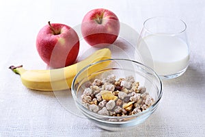 Healthy food with Corn Flakes cereal in a bowl, apple, banana and glass with milk. Morning breakfast.