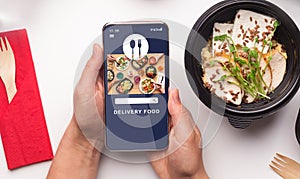 Healthy food delivery and modern gadgets. Male hands holding smartphone with online meal ordering app