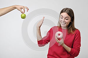 Healthy food and diet concept. Beautiful young woman choosing between fruits and sweets.