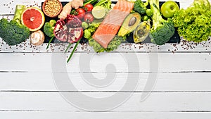 Healthy food. Fish salmon, avocado, broccoli, fresh vegetables, nuts and fruits. On a white wooden background.