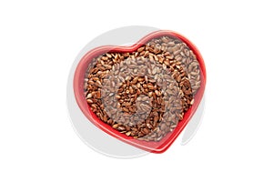 Healthy food. Flax seeds in red heart shaped bowl isolated on white background