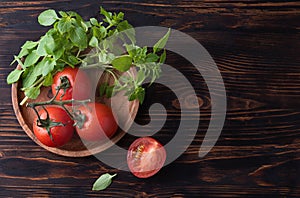 Healthy  food. Fresh aromatic basil and tomato on wood plate on a brown wooden background