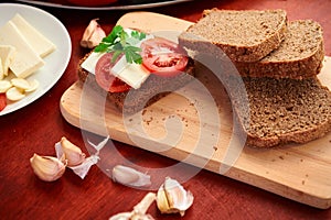 Healthy food - fresh bread and feta cheese on a wooden background, tomatoes, greens and vegetables