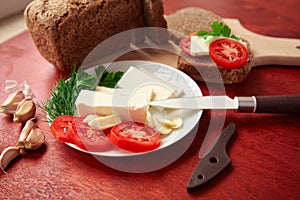 Healthy food - fresh bread and feta cheese on a wooden background, tomatoes, greens and vegetables