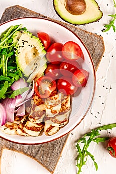 Healthy food. Greek salad with grilled Halloumi cheese, tomatoes, avocado, and arugula. Food recipe background. Close up.cuisine