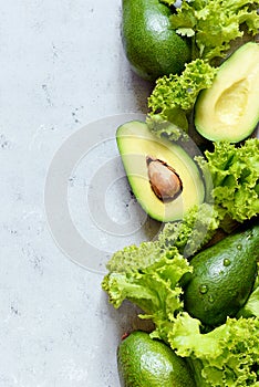 Healthy food. Half a ripe avocado with seed and lettuce on a plate on a gray background. Avocado salad Flat lay. Food concept.