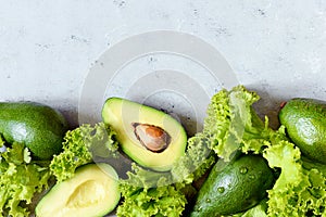 Healthy food. Half a ripe avocado with seed and lettuce on a plate on a gray background. Avocado salad Flat lay. Food concept.