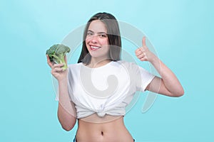 Healthy food, health lifestyle, diet. Beautiful woman eating fresh vegetable green broccoli, shows thumb up. Vegan meal