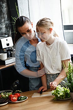 Healthy food at home. Happy family, mother and daughter are preparing salad. Woman and teenage girl are cutting