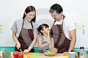 Healthy food at home. Happy multiethnic family Mum, Dad and daughter cooking in the kitchen preparing a salad together. Family and