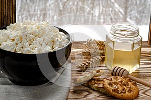 Healthy food: homemade cheese in a black round plate stands on a wooden table next to a jar of honey photo
