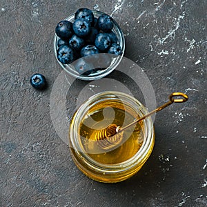 Blueberries and honey on dark background, top view photo