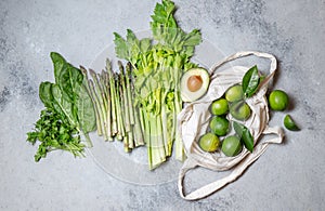 Healthy food ingredients gree vegetables and fruits on bamboo tray on gray background