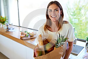 Healthy food keeps my smile bright. An attractive woman holding a bag of groceries in the kitchen.