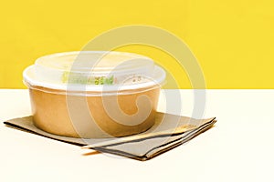 Healthy food lunch in kraft paper carton eco friendly box disposable bowl packaging container on yellow background. chicken, eggs