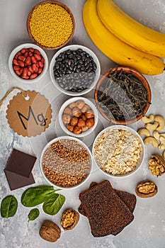 Healthy food nutrition dieting concept. Assortment of high magnesium sources. Banana chocolate spinach, buckwheat, nuts, beans, o photo