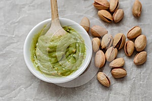 Healthy food, pistachio pasta and unpeeled salted pistachios, wooden spoon on a light background. Components for cooking
