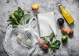 Healthy food planning concept. Eco bag, fruits, vegetables, greens and empty notebook on a gray background, top view with copy