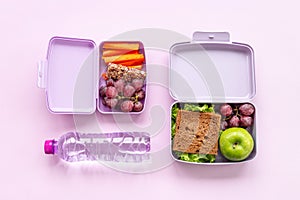 Healthy food in purple lunch boxes. Sandwich and fruits for fast meal