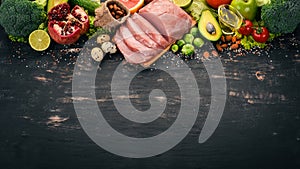 Healthy food. Raw meat, avocado, broccoli, fresh vegetables, nuts and fruits. On a wooden background.