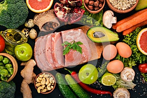 Healthy food. Raw meat, avocado, broccoli, fresh vegetables, nuts and fruits. On a wooden background.
