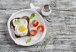 Healthy food - a sandwich with rye bread, soft cheese and boiled egg. On a light rustic wood surfaces.