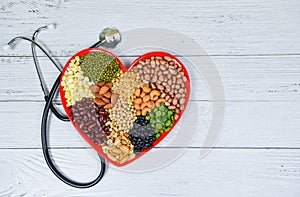 Healthy food selection clean eating for heart life cholesterol diet health concept - mixed various beans nuts grain on red heart