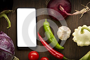 Healthy food and smartphone. Raw organic vegetables and fruits. On wooden background. Top view. Copy space