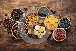 Healthy food snack: sun dried organic mix of dried fruits: apricots, figs, raisins, dates, and other on wooden table, top view