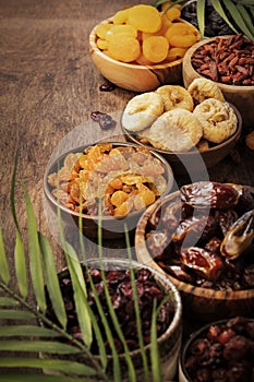 Healthy food snack: sun dried organic mix of dried fruits: apricots, figs, raisins, dates, and other on wooden table, top view