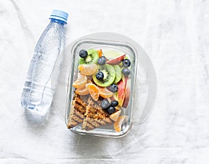 Healthy food snack sweet vitamin lunch box and bottle of clean water on a light background. Peanut butter toast, apples