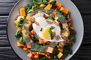 Healthy food sweet potato with kale, bacon and fried egg close-up on a plate. Horizontal top view