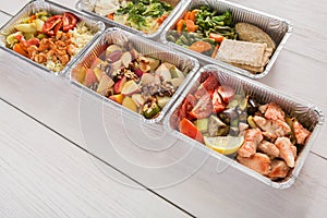 Healthy food take away in foil boxes on wood background