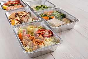 Healthy food take away in foil boxes on wood background