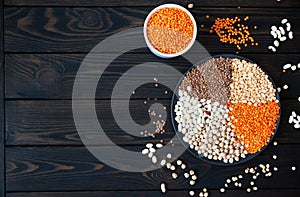 Healthy food of vegan and vegetarian. Plate with raw chickpeas beans and lentils on a dark background top view with empty space